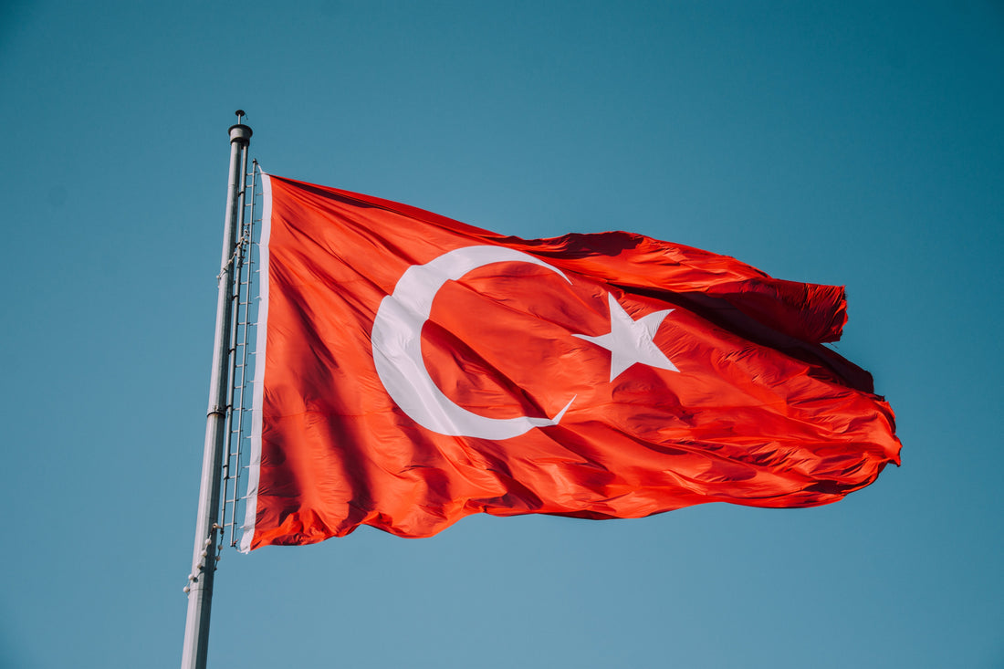 Mavi gökyüzünde dalgalanan Türk bayrağı — devlete bağlılık ve toplumsal barış çağrısını simgeleyen görsel.