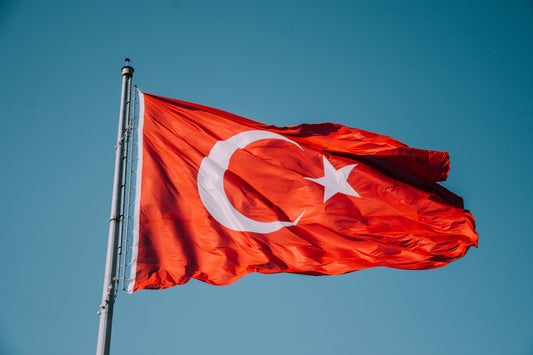 Mavi gökyüzünde dalgalanan Türk bayrağı — devlete bağlılık ve toplumsal barış çağrısını simgeleyen görsel.