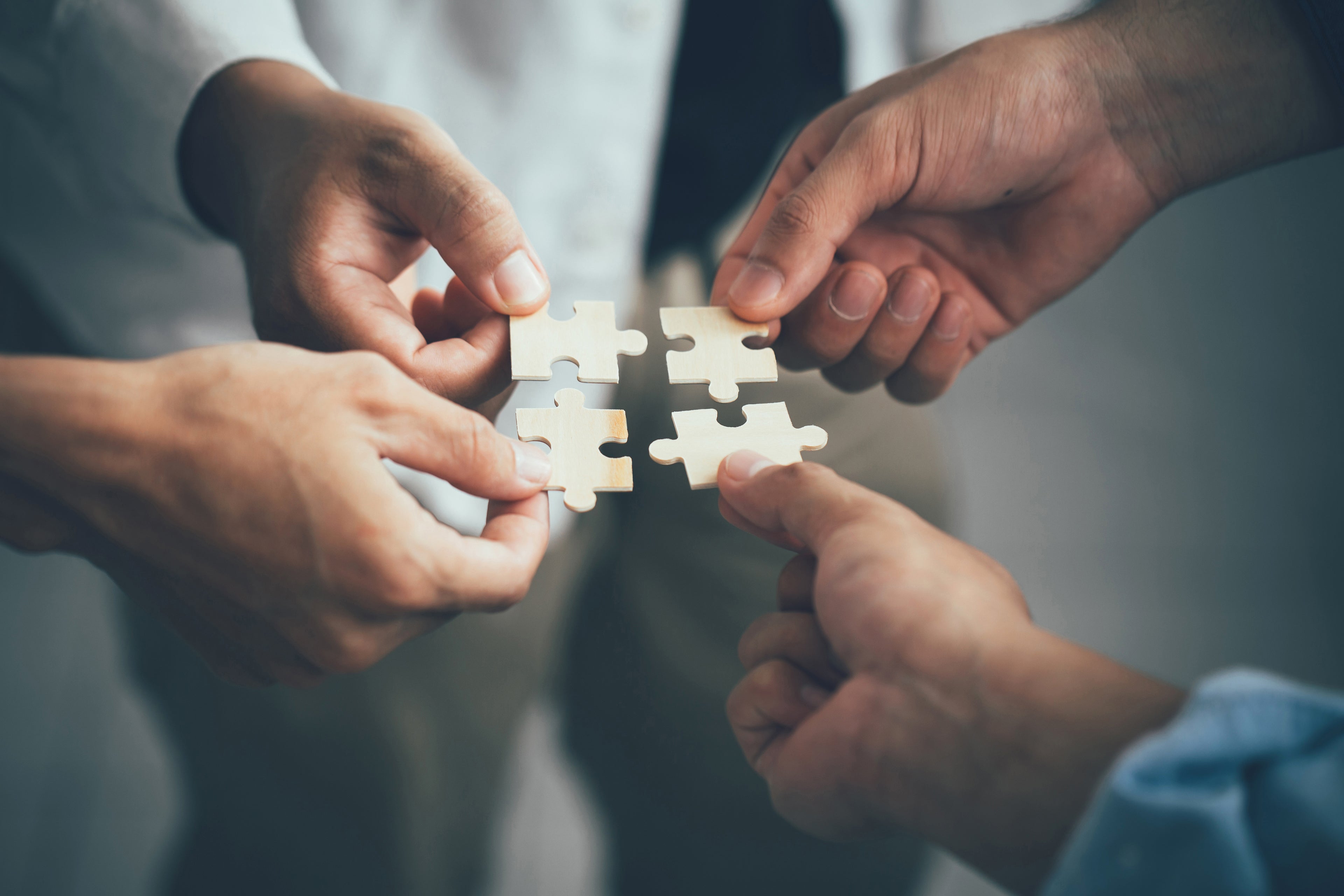 Farklı ellerin puzzle parçalarını bir araya getirmesi — toplumsal onarım ve ortak geleceği simgeleyen kapak görseli.